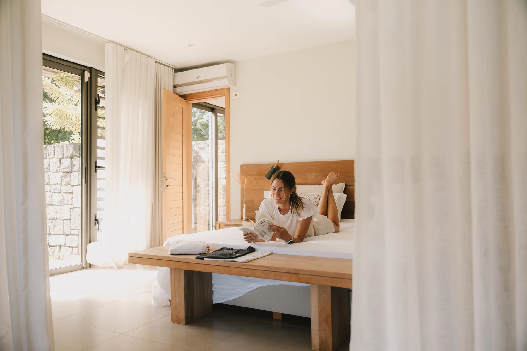 Ein Gast liest in einem hellen Zimmer mit offener Terrassentür